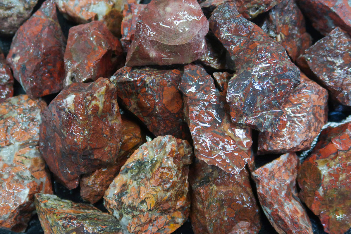 A close up picture of red jasper pieces that are approximately 1.5 inch in size. They have grey and white brecciations through the stones